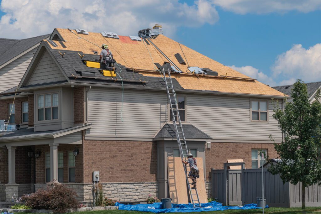The roofer's partner descends from the roof to get tools and turn on the compressor