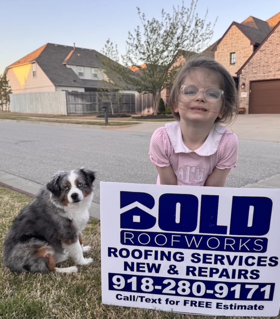 A young girl in a pink dress and glasses kneels next to a small dog beside a BOLD Roofworks yard sign on a suburban street. The sign reads “BOLD Roofworks – Roofing Services – New & Repairs – 918-280-9171 – Call/Text for FREE Estimate.”