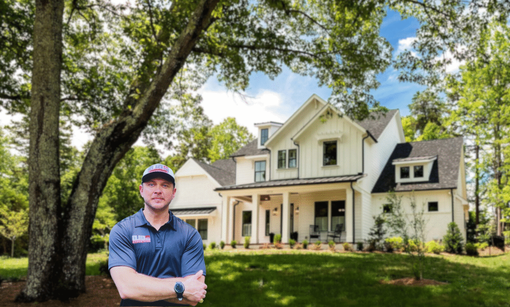 A roofing contractor wearing a BOLD Roofworks shirt and hat stands confidently in front of a large, modern white farmhouse surrounded by green trees and a well-kept lawn.